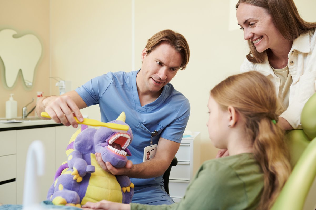 Pediatric dentist demonstrating tooth brushing to a child