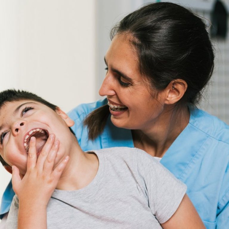Happy physiotherapist is assisting a laughing child with cerebral palsy during rehabilitation therapy